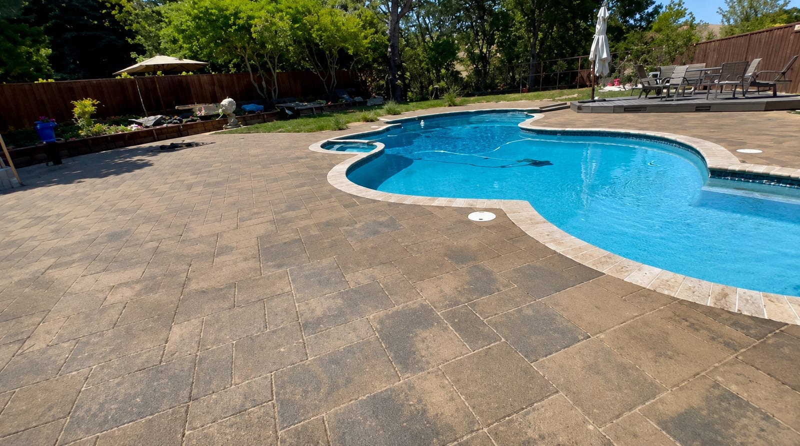 Curved paver pool deck with a light-colored surface installed by Royal Outdoor Solutions in the Bay Area