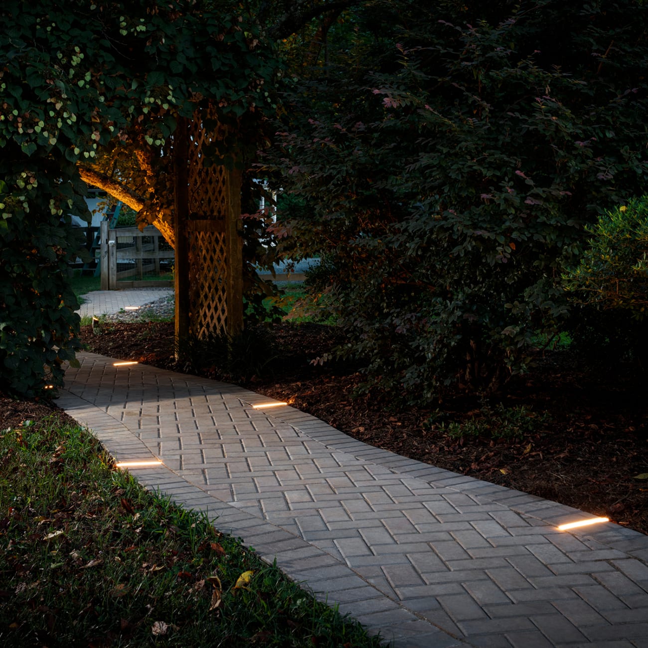 Herringbone paver walkway with low path lights set into the border, installed by Royal Outdoor Solutions